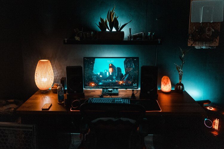 Setup de computador com luminárias sobre a mesa.