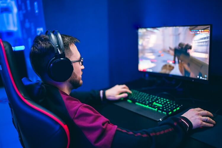 Homem de jaqueta vermelha e preta jogando no computador