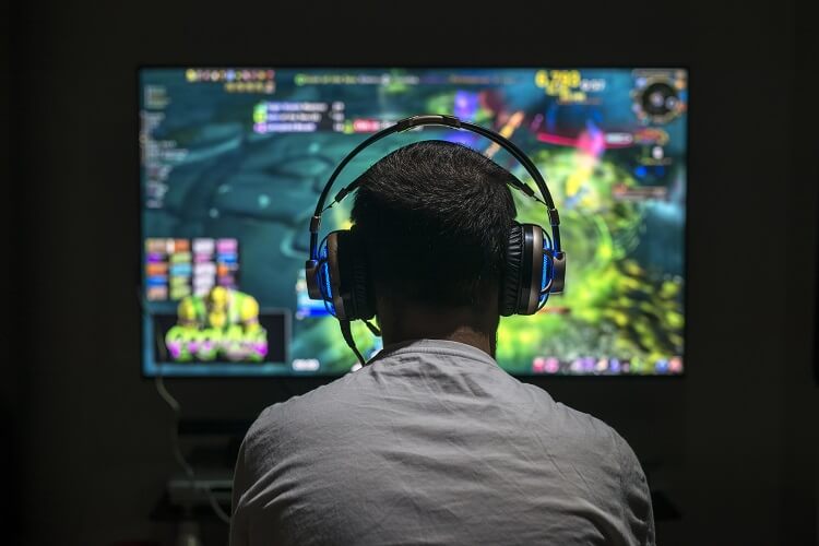 Silhueta de homem com fone na frente de computador.
