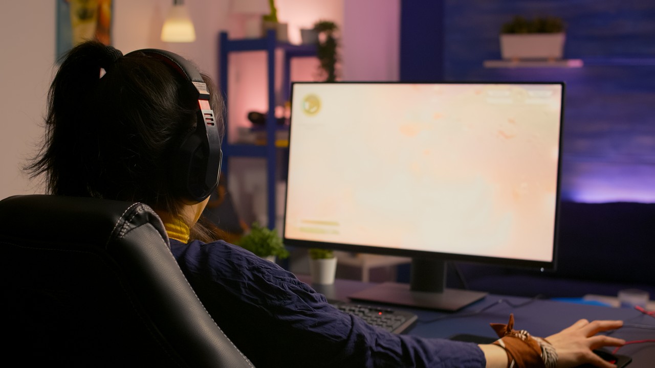 Mulher jogadora concentrada perdendo jogo virtual multijogador poderoso computador em casa com fones de ouvido profissionais