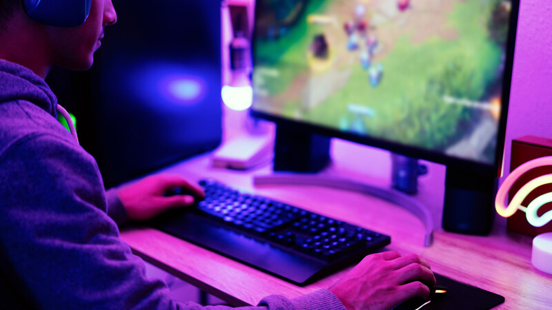 Jogador em ação com computador e teclado gaming.
